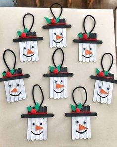 snowmen made out of popsicle sticks are hanging on the wall with hats and bows