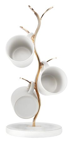 three white cups and saucers are on a stand with two gold rings in the middle