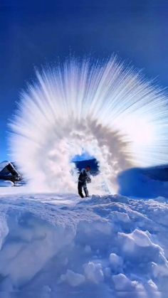 a man standing on top of a snow covered slope next to a large white object