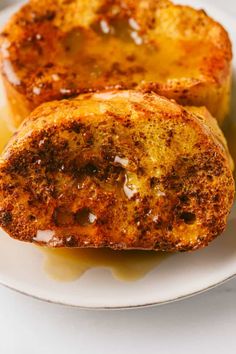 two pieces of bread sitting on top of a white plate covered in syrup and butter