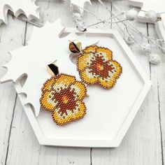 a pair of beaded earrings sitting on top of a white tray