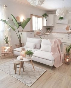 a living room filled with white furniture and lots of plants on top of a rug