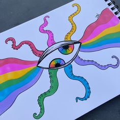 a spiral notebook with an eye drawn on the cover and rainbow colored lines coming out of it