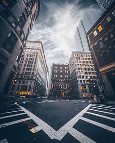 an empty city street with tall buildings in the background at dusk, looking up into the sky