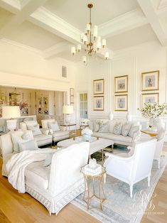 a living room with white furniture and chandelier