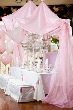 a table with pink and white balloons on it in front of a canopy over the tables