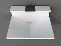 a white table with a black square light on it's side and a gray wall in the background