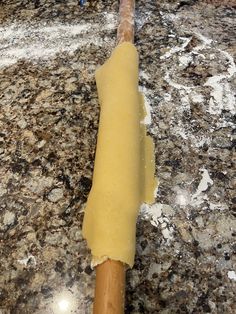 an uncooked pizza dough on a wooden rolling pin in the middle of a granite countertop