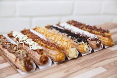 five different types of food are on a wooden table with white brick wall in the background