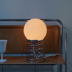 a lamp sitting on top of a table next to a white cup and saucer