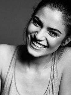 a smiling woman with her hair in a bun and wearing a tank top is looking at the camera