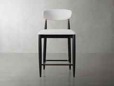 a white chair sitting on top of a floor next to a gray wall with a wooden frame