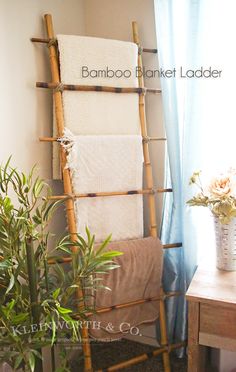 a bamboo towel rack in the corner of a room next to a potted plant