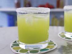 two glasses filled with green liquid sitting on top of a table