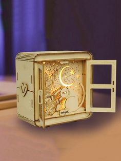 an open box shaped like a clock with the moon and stars on it sitting on a table