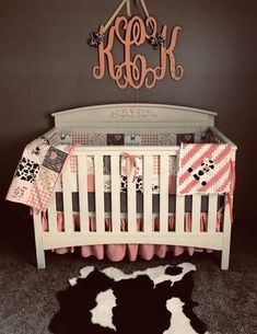 a white crib with pink and black bedding in front of a gray wall