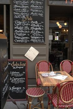 tables and chairs in front of a restaurant with menus on the wall