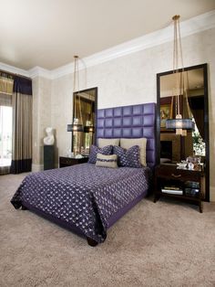 a bedroom with a large bed and purple comforter on the floor next to a window