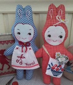 two small stuffed animals sitting next to each other on top of a table with scissors and thread