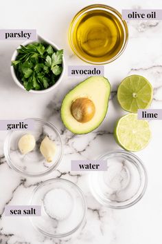 ingredients to make an avocado salad laid out on a marble counter top