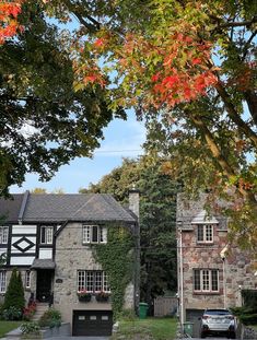 a car parked in front of a stone house with red leaves on the tree branches