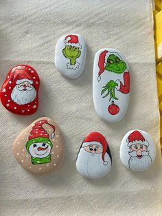 six painted rocks with santa claus, grino and snowman faces on each rock