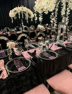 the table is set with black and pink linens, silverware, and floral centerpieces