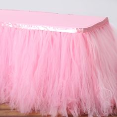 a pink tulle table skirt sitting on top of a wooden floor