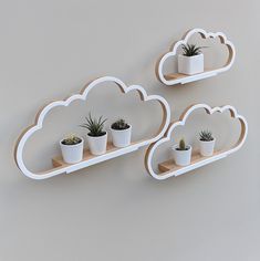 two white shelves with potted plants on them, one is shaped like a cloud