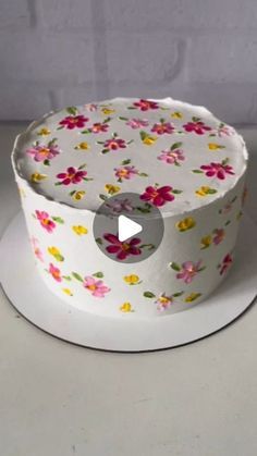 a white cake with pink and yellow flowers on it