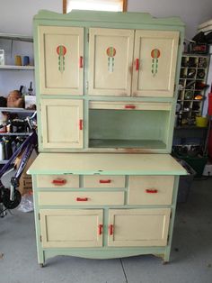 an old dresser is painted green and has red knobs on the top, with two doors