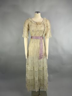 "A rare beautiful authentic 1900's floral print day dress INFO  * Circa - 1900s - 1910 * Label - n/a * Color - beige lavender * Material  - fine netting, silk, satin * Condition - slight fading  to underarms, large older repair to net on skirt   presents beautifully DETAILS - - antique Titanic style dress - inner layer of cream silk - outer layer of printed floral fine net - scoop neckline piped in  lilac - small ribbon rosette at neck - it has a delicate lace ruffle edge - elbow length sleeves with ruched detail - cuffs are edged with ruffle lace - bodice closes with  hooks and eyes - lace and piping hid closure - slight empire waist with satin cummerbund - lilac satin tie falls from waist - hem of skirt has 3 net and ruffle panels - beautiful, delicate, romantic  historical dress PJ10021 Whitepine Aesthetic, Floral Net Dress, 1910 Fashion Women, Tea Attire, 1900 Dresses, 1900 Dress, 1912 Fashion, Edwardian Dresses, Edwardian Gowns