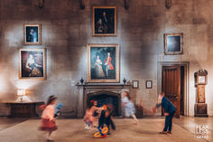 children are playing in an old building with paintings on the walls and fireplaces behind them