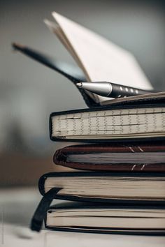 a stack of books sitting on top of each other with a pen sticking out of one book