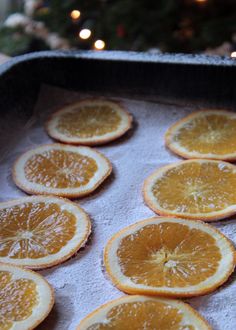 orange slices are arranged on a baking sheet in front of a christmas tree and lit candles