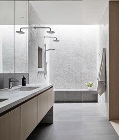 a modern bathroom with gray tile and wooden cabinets, along with a large bathtub