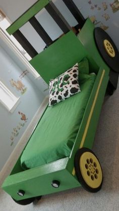 a bed made to look like a car with wheels on the bottom and green bedspread