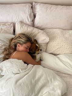 a woman laying in bed with her dog