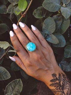 "A large statement crystal ring made of gold stainless steel with an adjustable band. The ring features a round polished larimar gemstone in AAA quality of 2cm in diameter. Larimar is also known as \"Stefilia's Stone\", it has a unique blue variety of the silicate mineral pectolite and this stone is only sourced from the Dominican Republic, found in the Caribbean. Gemstone: Natural/Genuine Larimar Sourced from The Dominican Republic Metals: Stainless Steel Hypoallergenic Waterproof Ring Size: Ad Labradorite Properties, Larimar Crystal, Energy Jewelry, Silicate Minerals, Larimar Rings, Larimar Stone, Gold Statement Ring, Gift For Sister, Labradorite Jewelry