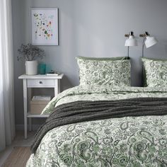 a bed with green and white bedspread in a bedroom next to a window