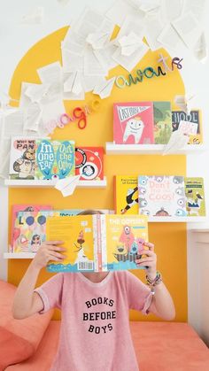 a person sitting on a bed holding up a book in front of their face with the words books before boys above them