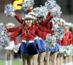 a group of cheerleaders in red and blue outfits are marching down the field