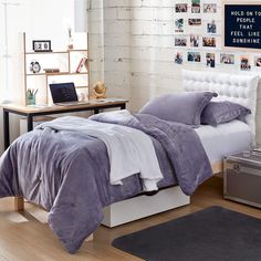 a bed with purple sheets and pillows in a bedroom next to a desk, chest of drawers and pictures on the wall