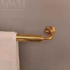 a close up of a towel hanging on a gold colored curtain rod in a bathroom