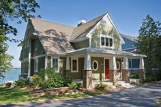 a large house with lots of windows and green siding on the front of it, along with a red door