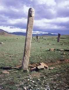 a stone pillar in the middle of a grassy field