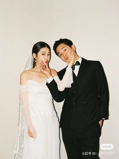 a bride and groom pose for a wedding photo in front of a white wall with the words love written on it