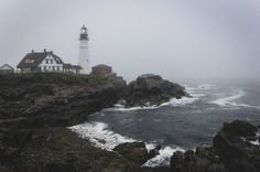 a light house sitting on top of a rocky cliff next to the ocean with waves crashing in front of it