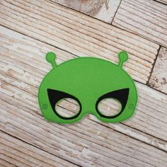 a green mask with black eyes on a wooden surface