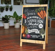 a blackboard sign sitting on top of a wooden table next to potted plants